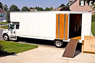 Moving truck with office furniture and packed boxes ready for transport.