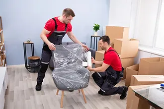 Team of professional movers carefully packing office supplies and furniture.