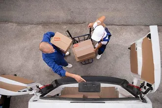 Mover pushing a dolly loaded with boxes indoors.