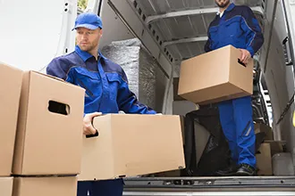 Mover carrying cardboard boxes while wearing blue uniform.