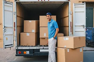 Worker unloading moving boxes from a truck, symbolizing long-distance moving services.