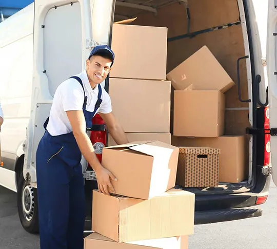 Mover in uniform unloading boxes from a truck during a relocation.