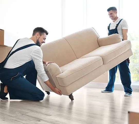 Mover lifting a couch while assisting with home relocation.
