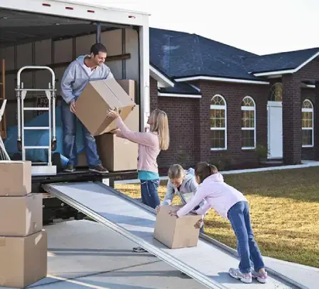 Movers carrying boxes up the stairs of a residential home.