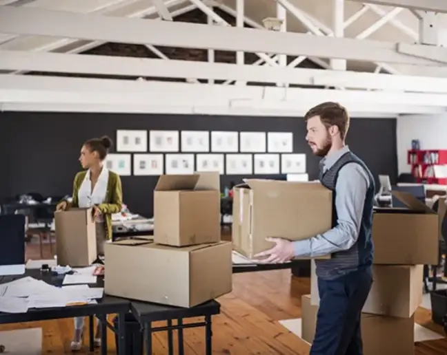Professional movers carrying boxes and organizing an office relocation.