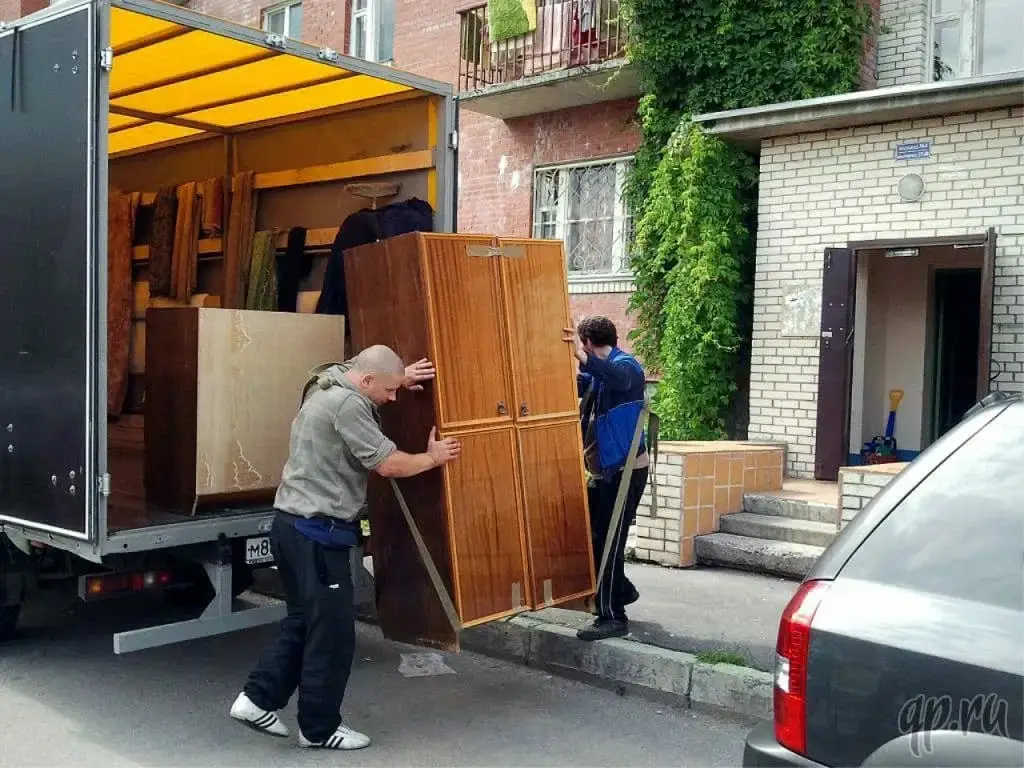 Movers loading a wooden wardrobe onto a truck in Midwest City, OK.