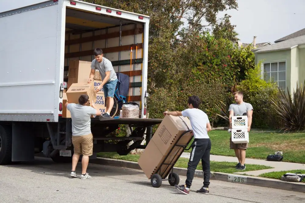A team of movers is unloading a truck in a residential area of Oklahoma City, OK, working efficiently to transport boxes and furniture with teamwork and care.