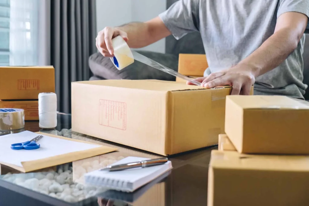 A person is carefully packing boxes using tape, preparing for a move in Oklahoma City, OK.