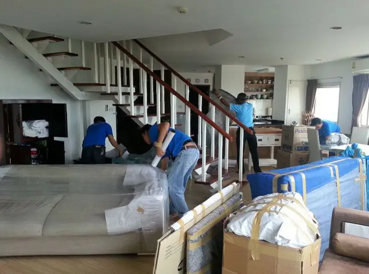 Professional movers are carefully packing and securing furniture in a home, ensuring a smooth relocation in Oklahoma City, OK.