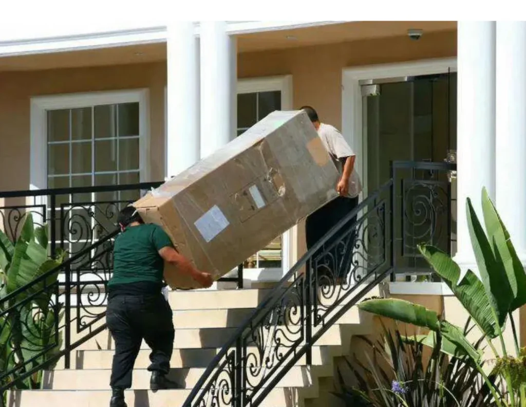 Two movers carrying a large box up the stairs of a home in Midwest City, OK